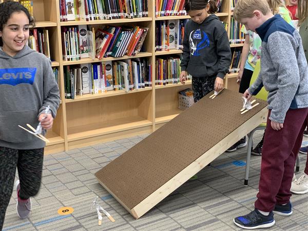Students race their skiiers made with aluminum foil and popsicle sticks.